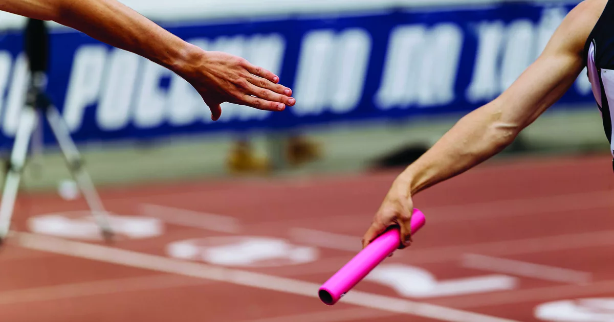 Auf dem Foto sind die Hände von zwei Athleten zu sehen, die sich den Staffelstab bei einem Staffellauf übergeben. Foto: Envato.